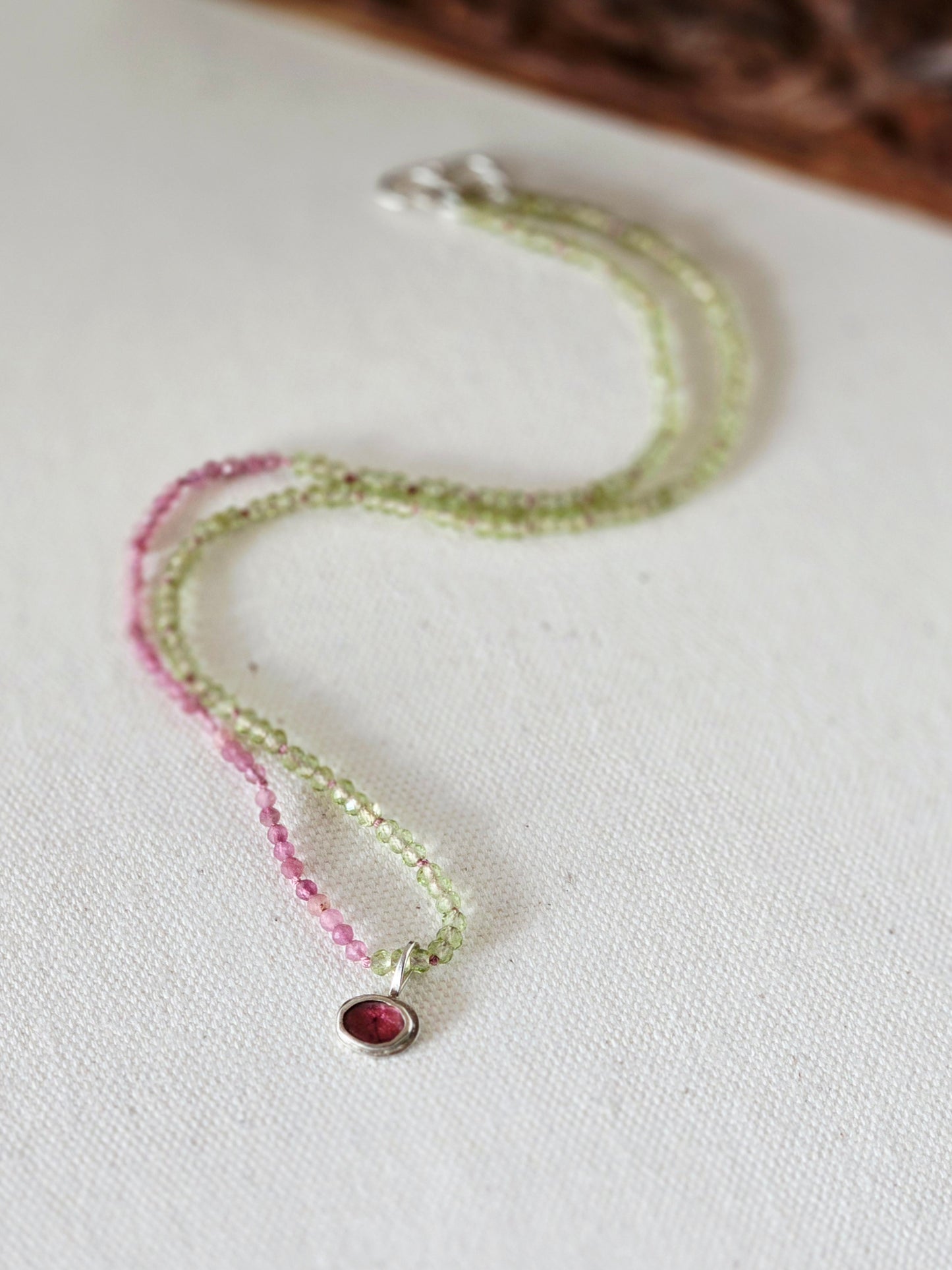 Necklace with pink and green beads on a white fabric background