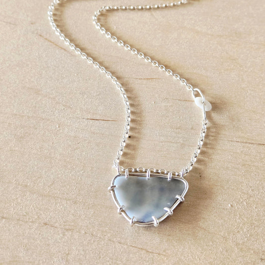 Necklace with a shell fragment pendant on a beige background