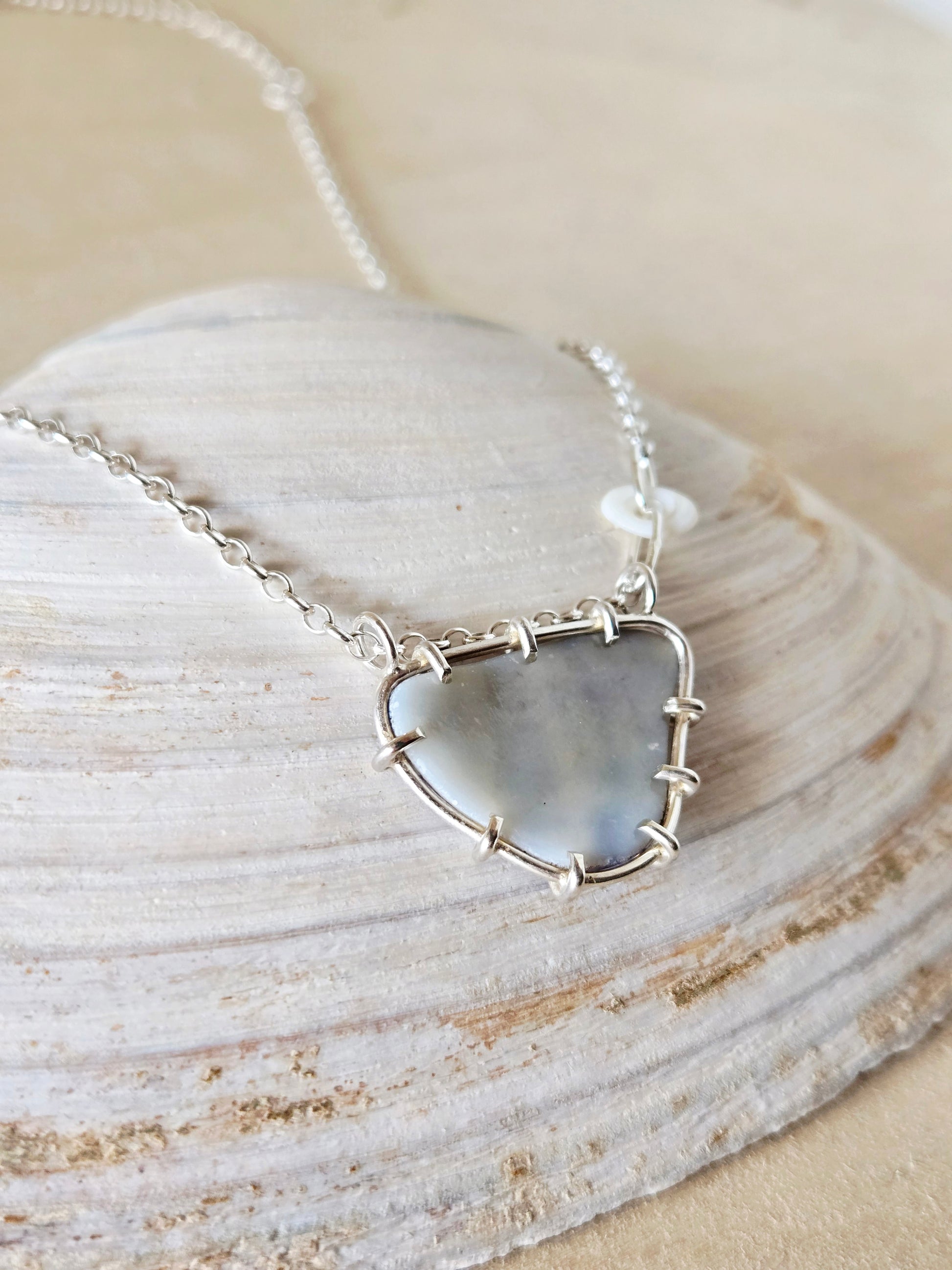 Necklace with a shell fragment pendant on a shell background