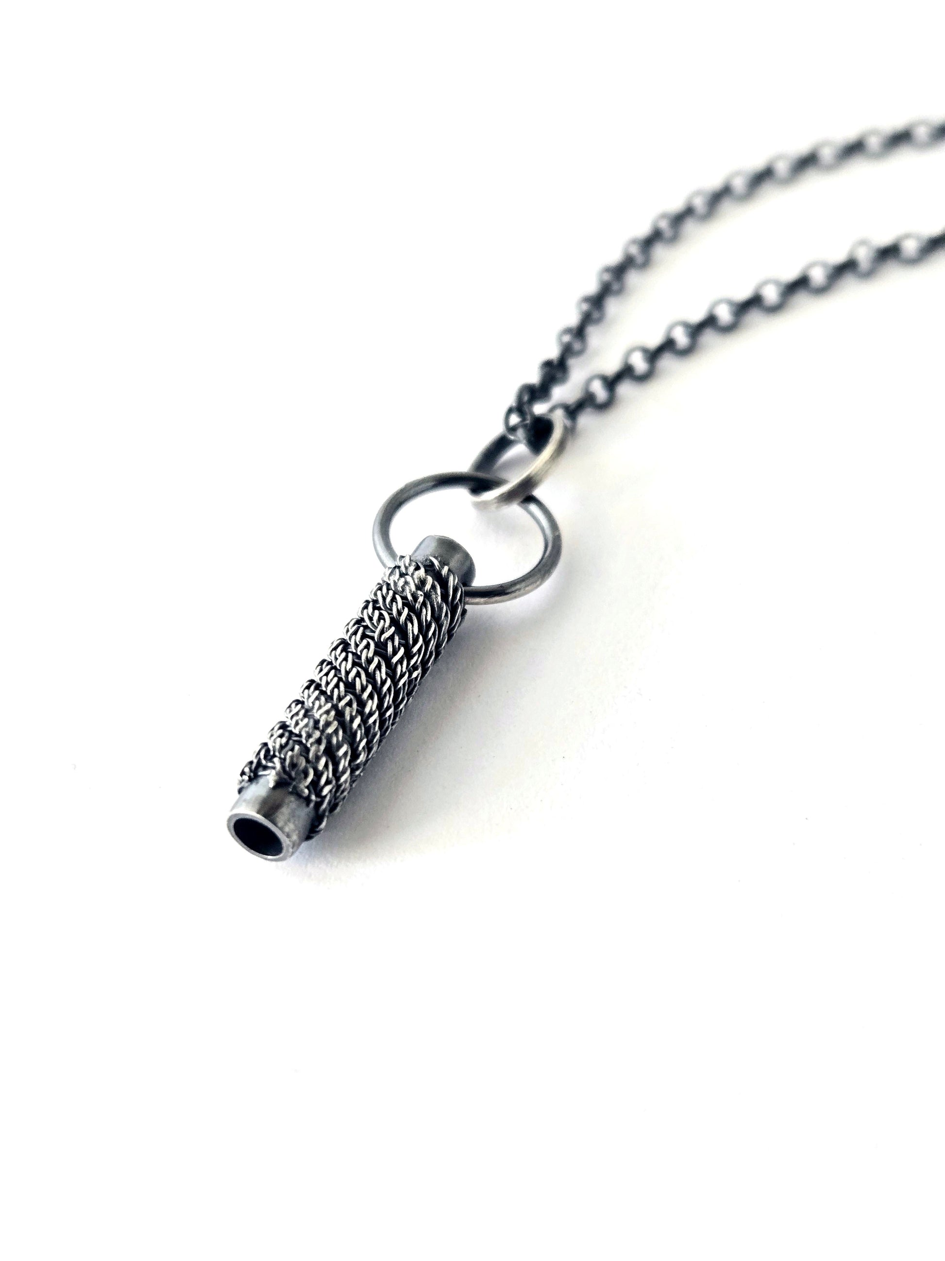 Silver necklace with a cylindrical pendant on a white background