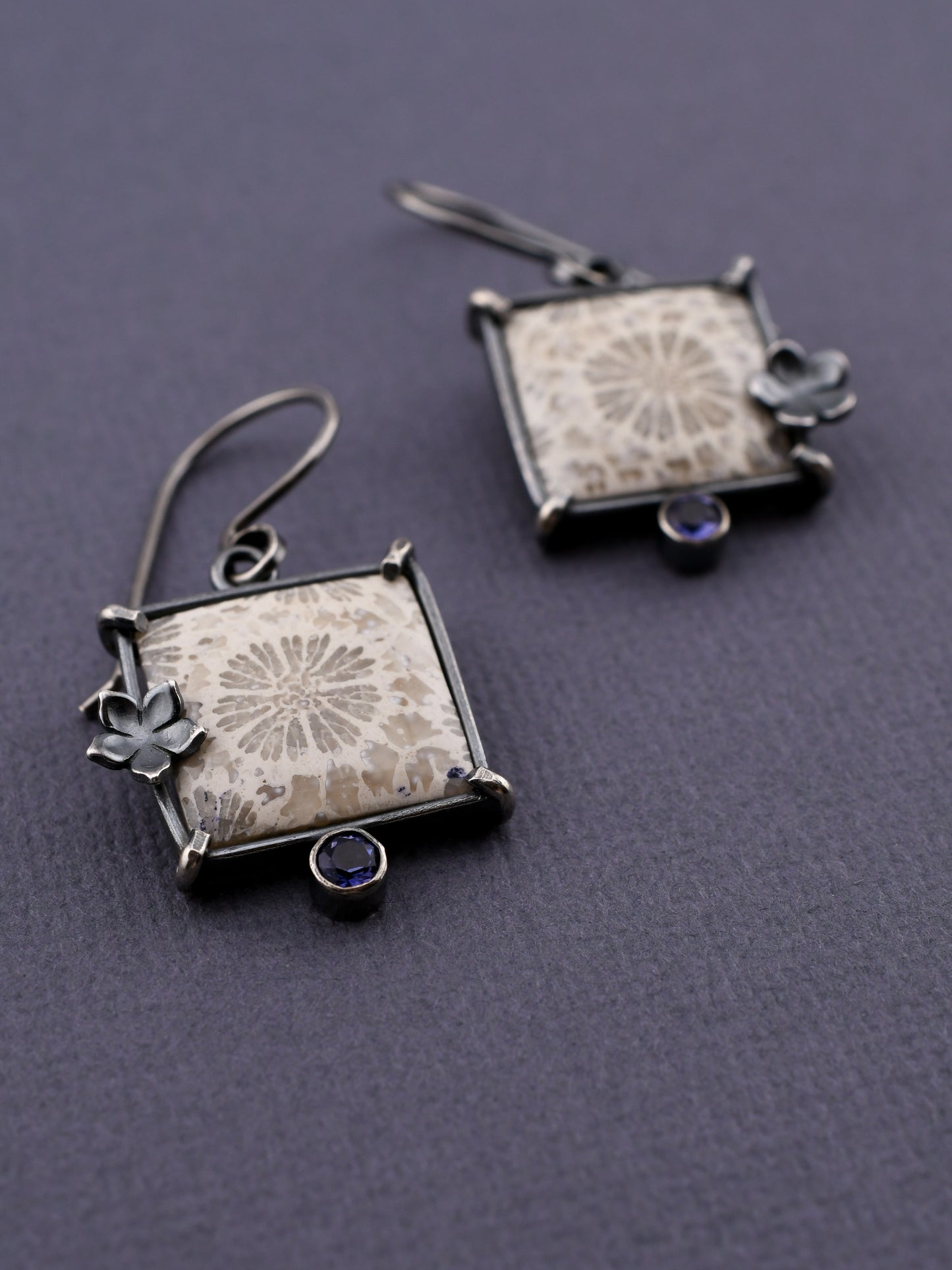 Pair of square earrings with floral designs on a gray background