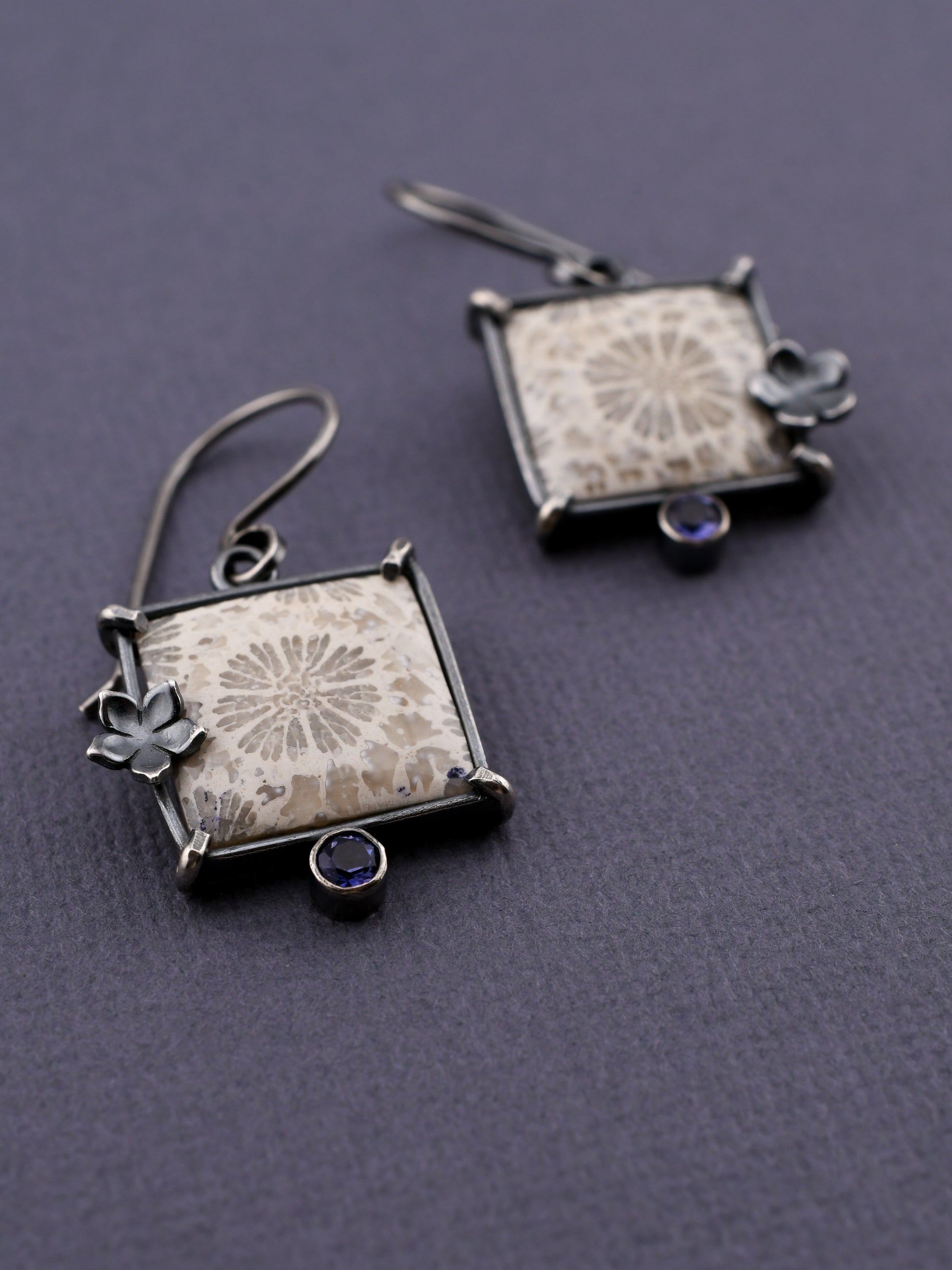 Pair of square earrings with floral designs on a gray background