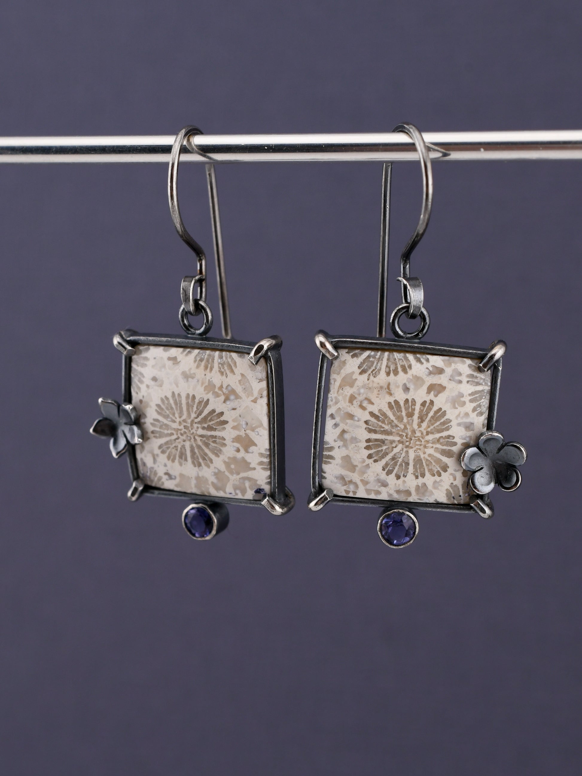 Pair of square earrings with floral designs on a dark background