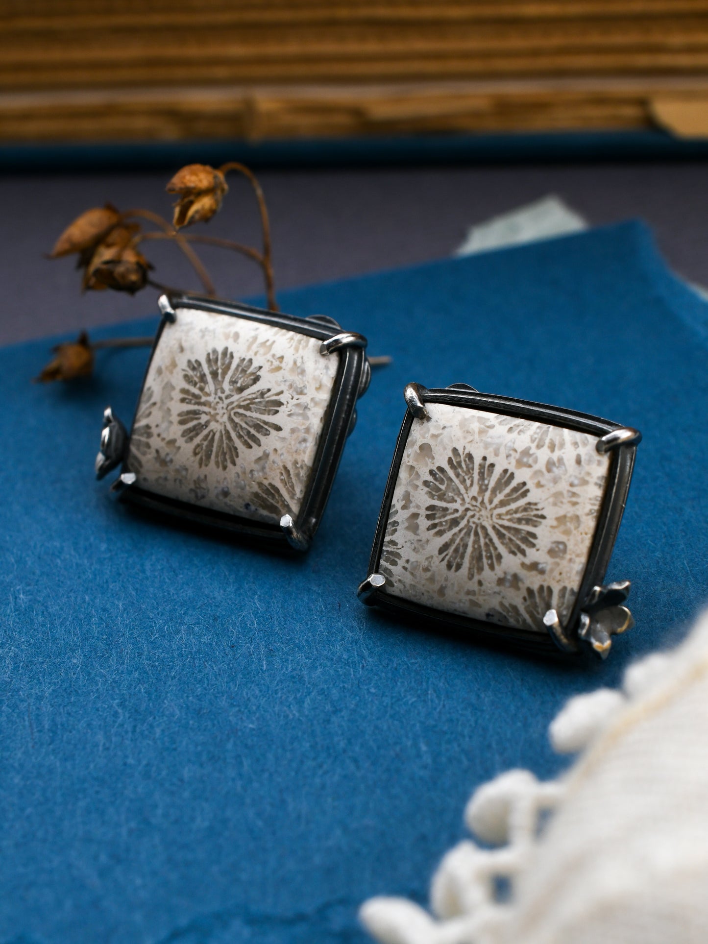 square stone earrings on blue with dried flowers and lace and a book in the background
