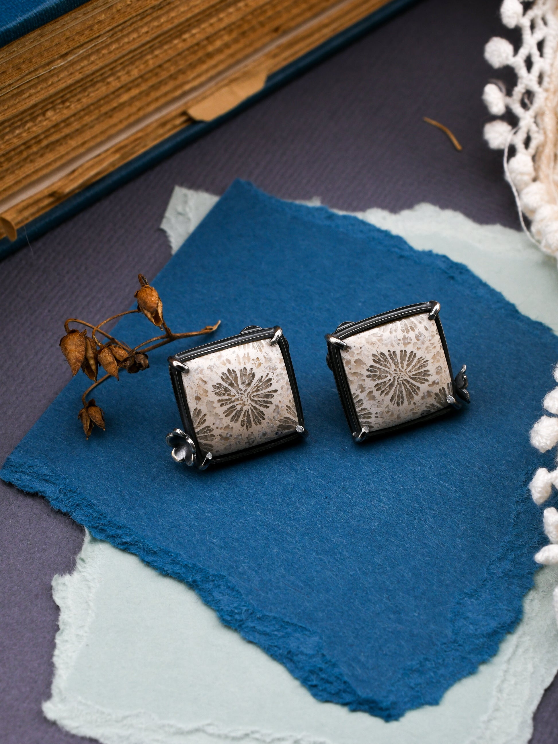 square white stone earrings on blue background with a book and lace